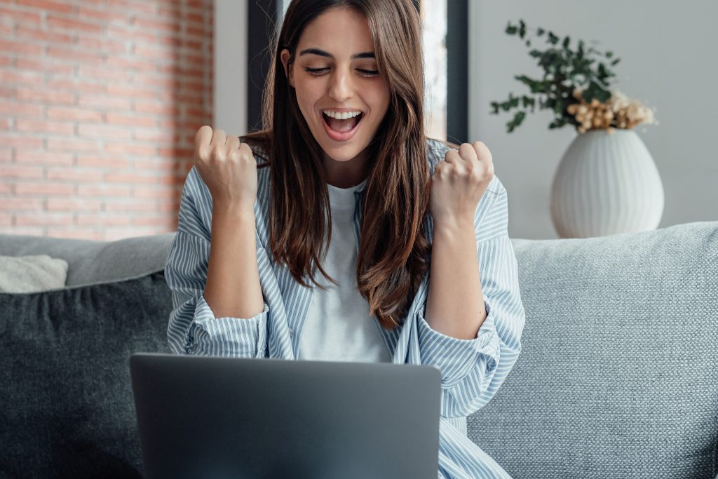 Vrouw reageert blij op haar laptop nadat ze snel duidelijkheid kreeg over een lening