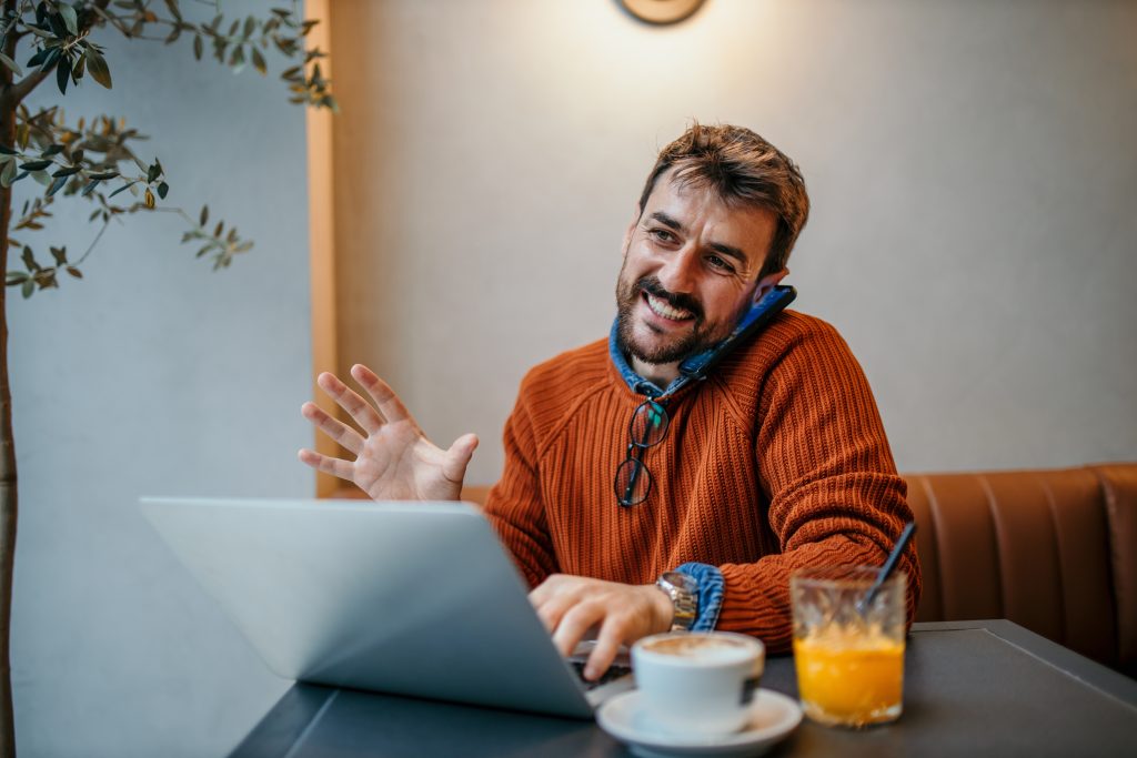 Man werkt achter laptop en belt terwijl hij informatie bekijkt over geld lenen met een wisselend inkomen