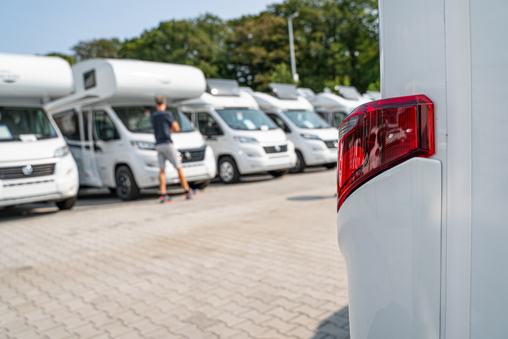 Rij campers op een verkoopterrein met een persoon die campers bekijkt.