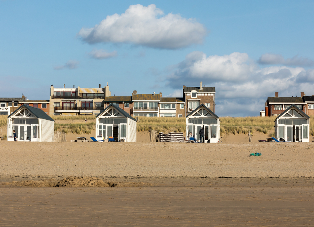 Strandhuisjes en woningen achter de duinen als symbool voor een vakantiehuis kopen.